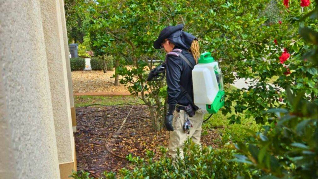 Professional Pest Control Near Me technician spraying eco-friendly treatment around the perimeter of a residential home to prevent pests.